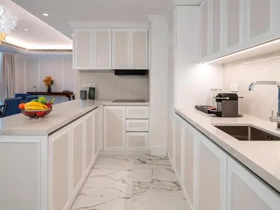 a kitchen with white cabinets and a bowl of fruit on the counter at Cheval Maison - Expo City Dubai in Dubai