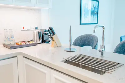 a kitchen counter with a sink and some chairs at Cheval Maison - Expo City Dubai in Dubai