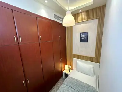 a bedroom with a bed and wooden cabinets at Destination Partition Room in Tecom Near Metro in Dubai