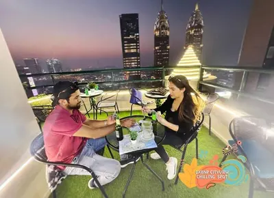 a man and woman sitting at a table on a balcony at Beautiful Partition Room in Barsha heights in Dubai