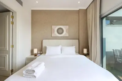 a bedroom with a large white bed and a window at Livbnb - Homey 1B with Spacious Terrace in District 14, JVC in Dubai