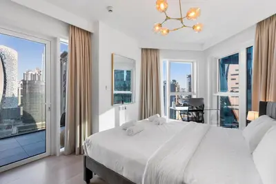 a bedroom with a large white bed and large windows at LUX 2BR in Missoni Tower - 5 mins to Burj Khalifa in Dubai