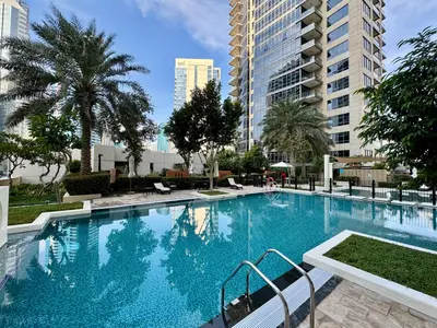 a large swimming pool with palm trees and buildings at Exquisite centrally located 1BR in Downtown Dubai in Dubai