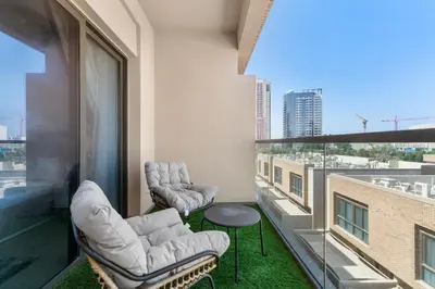 a balcony with two chairs and a table on a building at NEW! Spacious 2BHK with Maids room - JVC in Dubai