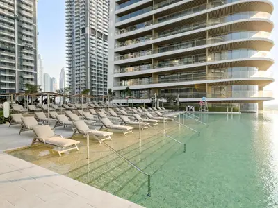 a swimming pool with chairs and a building at Elegant 2BR with Palm & Sea View l Direct Beach Access in Dubai