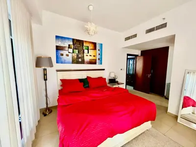 a red bed in a white bedroom with a red blanket at Bahar 6 in Dubai