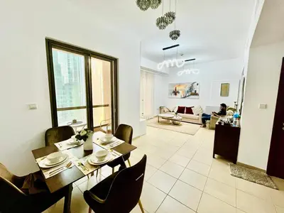 a dining room and living room with a table and chairs at Bahar 6 in Dubai