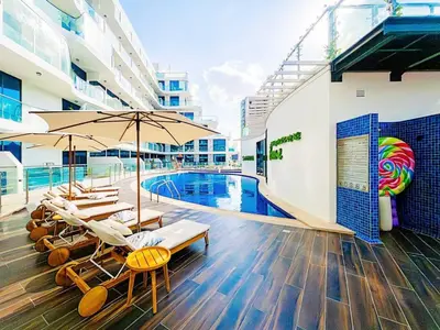 a pool with chairs and umbrellas next to a building at Arjan Bright Studio w Resort Amenities Samana PV by Vibel in Dubai