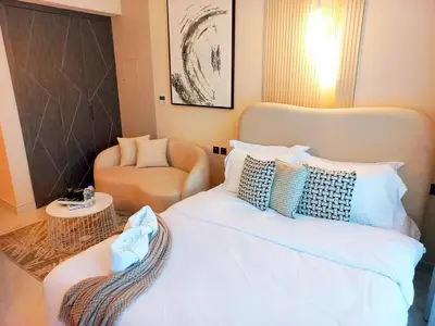 a bedroom with a white bed and a chair at Arjan Bright Studio w Resort Amenities Samana PV by Vibel in Dubai