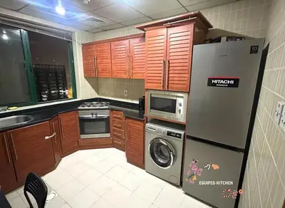a kitchen with wooden cabinets and a refrigerator at Familiar Partition Room In Tecom Near ICM Metro in Dubai