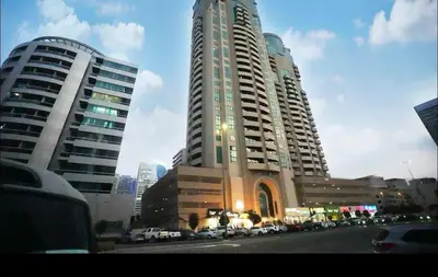 two tall buildings with cars parked in a city at The Junction Partition Room In Barsha Heights in Dubai
