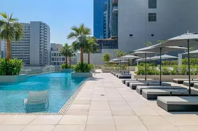 a swimming pool with lounge chairs and umbrellas at Vogue Downtown The Sterling by Omniyat, near Burj Khalifa and Dubai Mall, Studio Apartment with Balcony and Access to all Amenities in Dubai