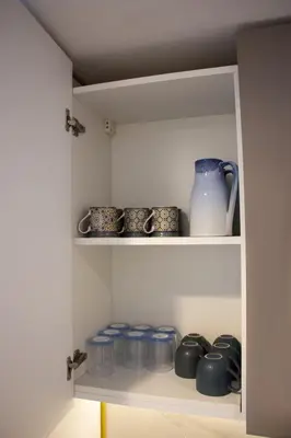 a shelf with blue cups and a vase on it at Modern Studio 15mins away From World Trade Center in Dubai