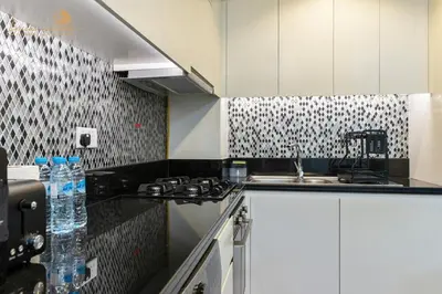 a kitchen with white cabinets and black and white tiles at Exclusive Sea-View 3Bhk 6pax in Dubai
