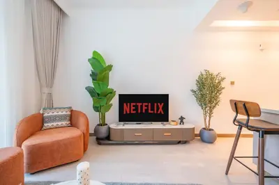 a living room with two chairs and a tv at Sleek and Stylish 1BR Fully Furnished Apt in Dubai
