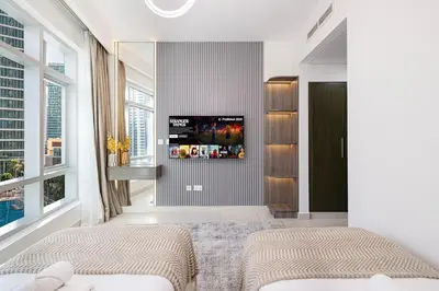 two beds in a bedroom with a tv on the wall at Beautiful 2 BR Apartment next to Opera I Burj View in Dubai