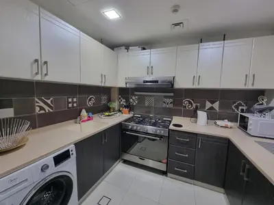 a kitchen with white cabinets and a washing machine at The One by Anu in Dubai