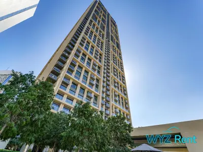 a tall building with a tree in front of it at Sleek 1BR w Canal Views Next to Dubai Mall in Dubai