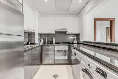 a large white kitchen with stainless steel appliances at Dubai Marina Elegant 1 BR on the Canal in Dubai