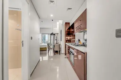 a kitchen with white floors and wooden cabinets at LUX Apt 5 min away from Burj Khalifa & Dubai Mall in Dubai
