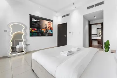 a white bedroom with a large white bed and a tv at Stunning 1 BR in JBR Dubai Marina The Walk in Dubai
