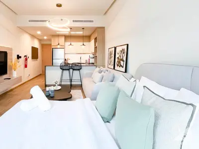 a living room with a white couch and a kitchen at Rokane G25 Studio Modern Comfort with City Views in Dubai