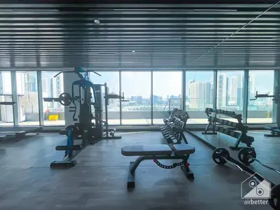 a gym with cardio equipment in a large room with windows at Rokane G25 Studio Modern Comfort with City Views in Dubai