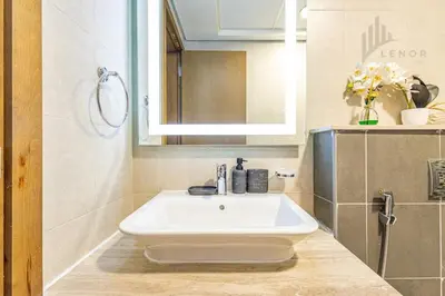 a bathroom with a white sink and a mirror at Modern 2BR Glowing Palm Trees Near Downtown in Dubai