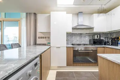 a kitchen with white cabinets and a counter top at Modern 2BR Glowing Palm Trees Near Downtown in Dubai