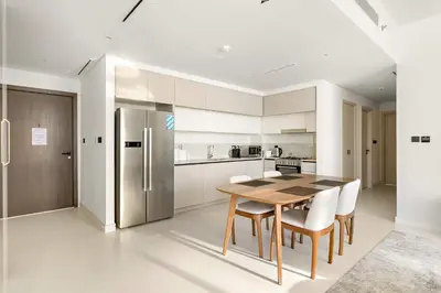 a kitchen with a wooden table and a refrigerator at Silkhaus Beachside Spacious 2BDR in Marina Vista in Dubai