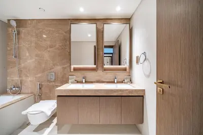 a bathroom with a sink and a toilet and a mirror at Homes Beyond I Stylish 2BR Beachfront Bliss in Dubai