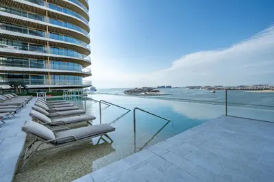 a row of lounge chairs on a balcony overlooking the water at Homes Beyond I Stylish 2BR Beachfront Bliss in Dubai