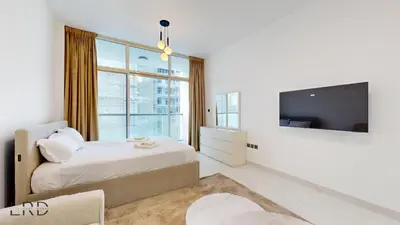 a white bedroom with a bed and a large window at Modern Furnished Studio in Dubai