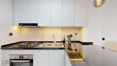 a white kitchen with a sink and a stove at Modern Furnished Studio in Dubai