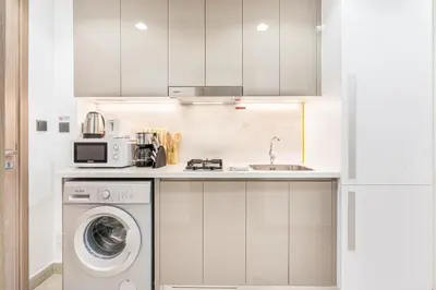 a kitchen with a washing machine and a microwave at Chic & Beautiful Home in the Heart of Meydan in Dubai
