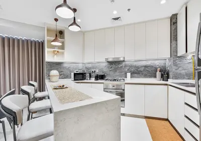 a kitchen with white cabinets and a counter with chairs at 2BR Central Apt in Business Bay Noble Tower in Dubai