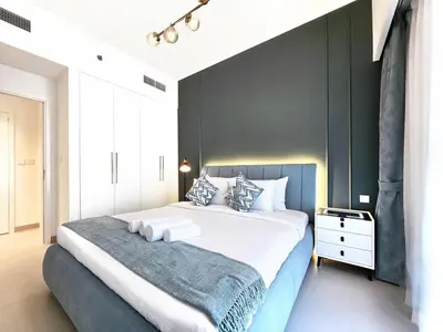 a bedroom with a large bed with a gray accent wall at Near Burj Khalifa, Dubai Fountain, Dubai Mall in Downtown in Dubai