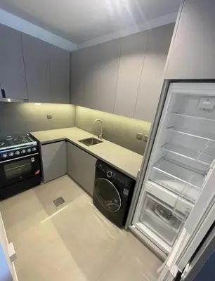 a small kitchen with a refrigerator and a sink at Brand New Designer 1-Bedroom Apartment With Free Parking in Dubai