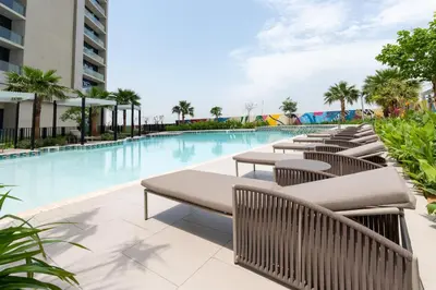 a pool with tables and chairs next to a building at Keyrock Living - Dubai Oasis with Balcony Views in Dubai