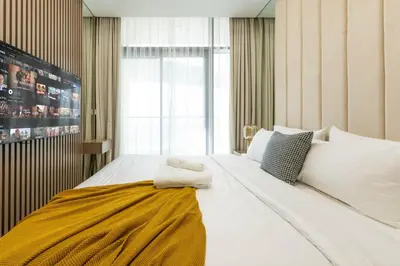 a bedroom with a large white bed with a yellow blanket at Keyrock Stylish Apartment in Dubai with Pool and Gym in Dubai