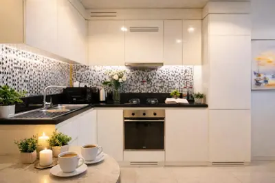 a kitchen with white cabinets and a table with cups on it at Keyrock Stylish Apartment in Dubai with Pool and Gym in Dubai