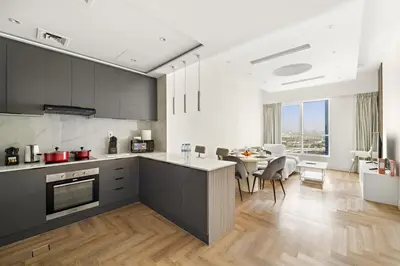 a kitchen with black cabinets and a table with chairs at Stylish 1BR with Balcony Near Marina Mall, Pool & Free Parking in Dubai