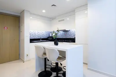 a kitchen with a white counter and stools at Keyrock Living - Elevated Luxury in Business Bay in Dubai