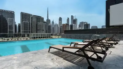 a pool with lounge chairs on the roof of a building at Keyrock Living - Binghatti Canal Luxury Stay in Dubai