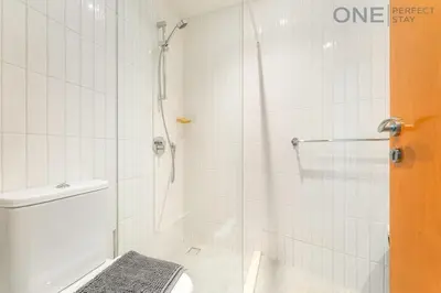 a white bathroom with a shower and a toilet at Stylish & Modern 3BR Apartment in Marina Stunning Views in Dubai