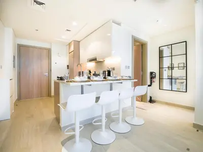 a kitchen with white bar stools and a counter at EasyGo- Splendid Apartments in Al Meydan Living in Dubai
