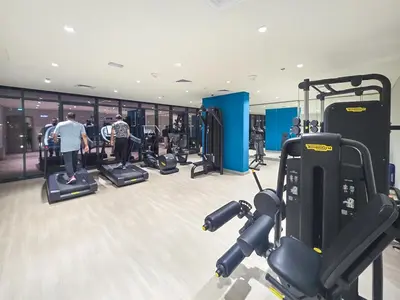 a gym with treadmills and people exercising in it at EasyGo- Splendid Apartments in Al Meydan Living in Dubai