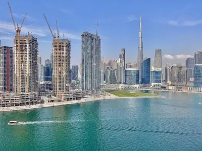 a boat in the water in front of a city at Panoramic! Burj Khalifa and Canal View! in Dubai