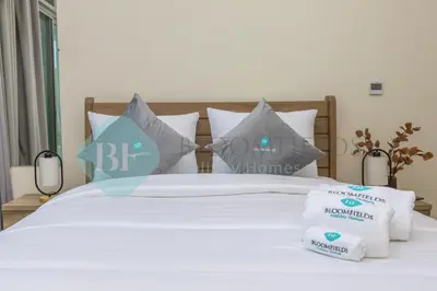 a bed with white sheets and pillows on it at Bloomfields Cozy Stu Azizi Farhad in Dubai