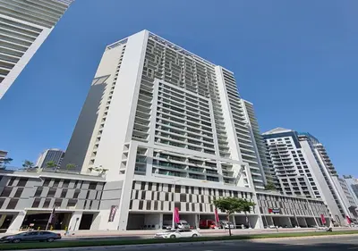 a tall white building with cars parked in front of it at Keyrock Living - 1BR at Reva Residence with Lake View in Dubai